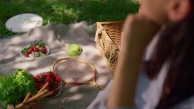 Piknik battaniyesinde oturan bir kadın. Çeşitli atıştırmalıklar. Yakın görüş bulanık.. 