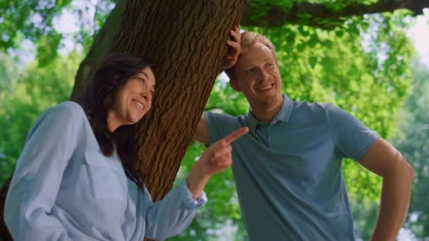 Schönes Paar im Gespräch lehnt sich an Baum aus nächster Nähe. Hübsche Frau lacht mit Ehemann. — Stockvideo