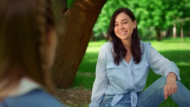 Usmívající se žena sedící v parku na trávě. Klidná matka pózující na přírodě — Stock video
