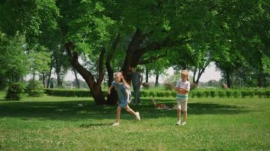 Yeşil çimenlerin üzerinde koşuşturan aktif kız. Neşeli çocuklar piknikte eğlenir..