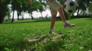 Aktif çocuk yeşil çimlerde topa tekme atıyor. Küçük sporcu parkta futbol oynuyor..