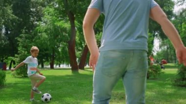 Çocuk, babasıyla yakın plan futbol antrenmanı yapıyor. Aile dışarıda futbol oynuyor..