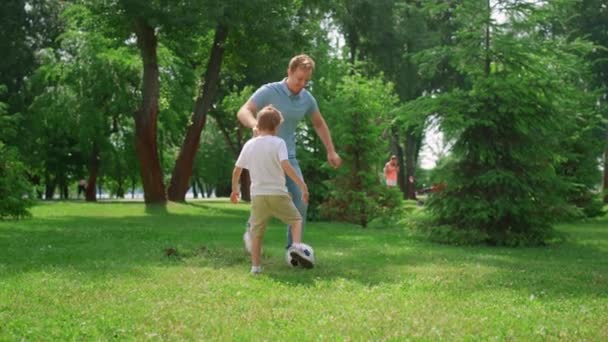 Boldog apa focit tanít a fiának. Vidám fiú passzol labdát apának a gyepen. — Stock videók