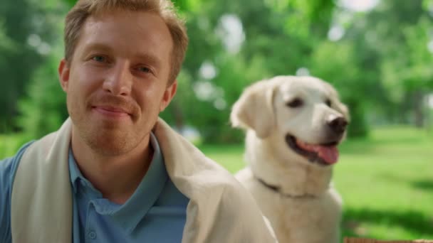 Retrato de hombre sonriente mirando a cámara con hermoso labrador en parque. — Vídeo de stock