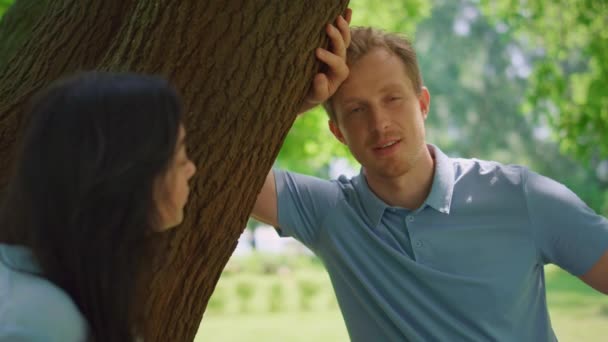 Spokojny mężczyzna rozmawiający z żoną pochyla się nad drzewem. Portret rodziny odpoczywającej — Wideo stockowe