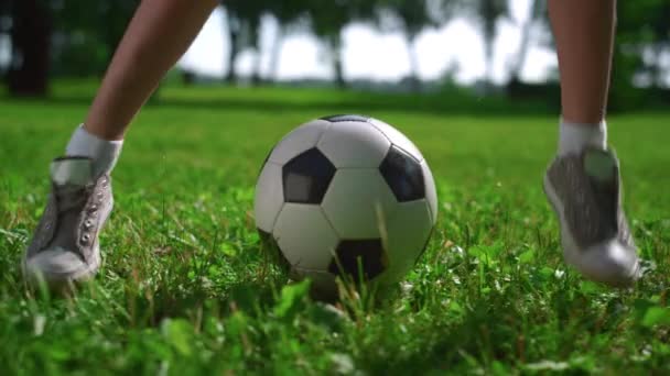 Szoros gyerek lábak futball trükköket csinálnak. Fiatal játékos gyakorlása a zöld mezőn. — Stock videók