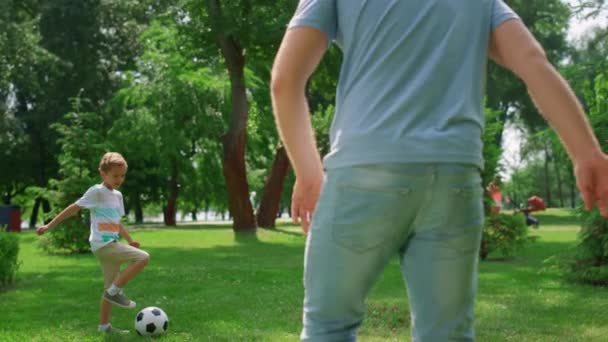 Çocuk, babasıyla yakın plan futbol antrenmanı yapıyor. Aile dışarıda futbol oynuyor.. — Stok video