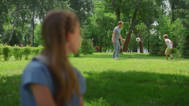 Профиль девушка смотрит футбол в парке. Отец играет в футбол с сыном. — стоковое видео