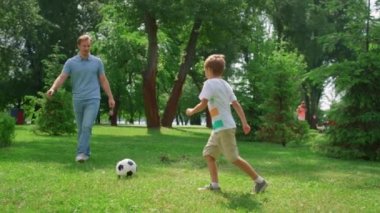 Yeşil Park 'ta aktif oğlana pas veren sporcu. Babam oğlanla futbol oynuyor.