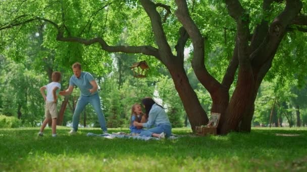 Familia activa divertirse en el prado del parque verde. Los padres juegan con los niños afuera. — Vídeos de Stock