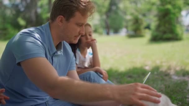 Jeu familial actif avec labrador tenant la tablette sur la pelouse. Père caresse labrador. — Video