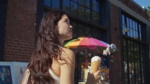Bruna gustare dessert freddo sulla passeggiata in città. Asiatico donna passeggiata mangiare gelato. — Video Stock