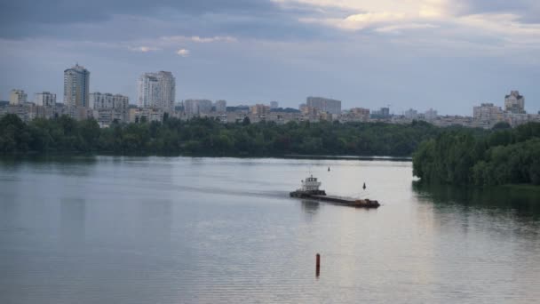 Drone schoot stadsgezicht op stromende rivieravond. Sleepboot duwt oude lege boot — Stockvideo