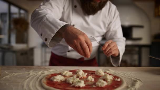Kuchyňský kuchař vaří pizzu v profesionální restauraci. Muž přidává koření na jídlo. — Stock video