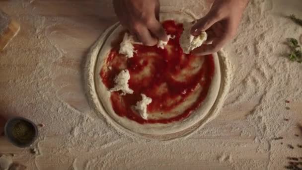 Chef koken zelfgemaakte pizza in de keuken. Banketbakker die kaas op deeg doet. — Stockvideo