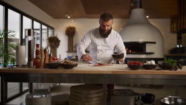 Homem cozinhando pizza italiana no restaurante. Chef espalhando molho de tomate na cozinha. — Vídeo de Stock