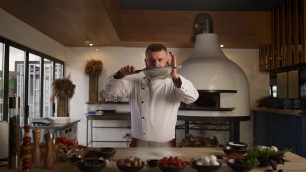 Jóképű séf lisztet szitál szitával a konyhában. Férfi főzés étteremben. — Stock videók