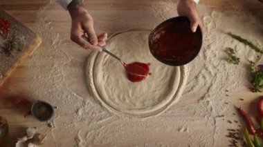 Şef pizzaya domates sosu sürüyor. Fırıncı mutfakta yemek pişiriyor..