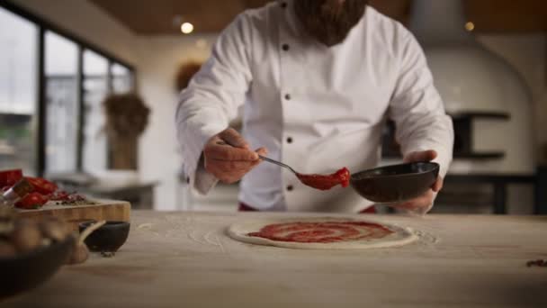 Cocinero profesional haciendo pizza en cocina culinaria. Chef hombre extendiendo ketchup. — Vídeos de Stock