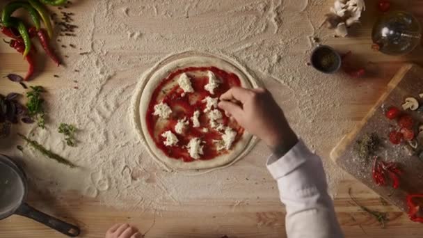 Homme faisant maison pizza pepperoni italien dîner sur table de cuisine. — Video