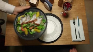 Garson, şık restoran masasına yemek tabağı koyuyor. Lezzetli yemek tabağı