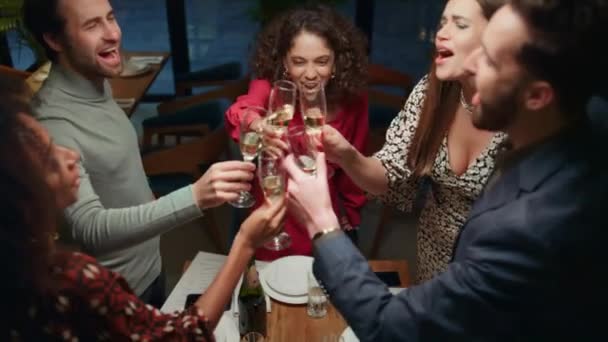 Jóvenes festejan juntos bebiendo alcohol. Amigos tintineo vasos en la cafetería. — Vídeo de stock