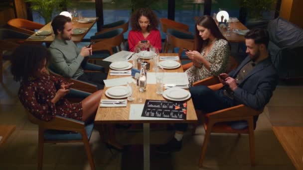 Multiraciale groep checkt telefoontoestel in café. Vrienden sms 'en in restaurant. — Stockvideo