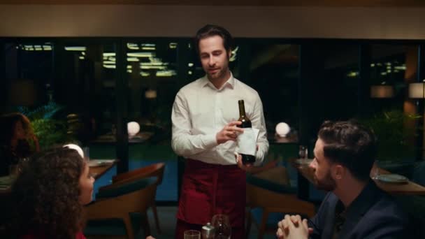 고급 카페 테이블에서 아름다운 부부를 위해 포도주를 부어 주는 레스토랑 웨이터. — 비디오