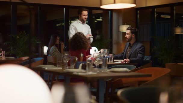 Ober serveert multi-etnisch paar op chique restaurant diner date 's avonds. — Stockvideo
