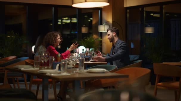 Par som använder mobiltelefon tar selfie i restaurang. Älskar firar tillsammans — Stockvideo