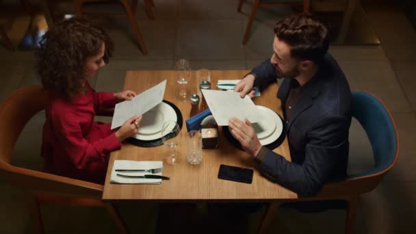 Attraktives Paar wählt Menü im Nachtrestaurant. Romantisches Dinner-Konzept. — Stockvideo