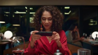 Lüks bir restoranda akıllı telefon kullanarak fotoğraf çeken süslü bir kadın.. 