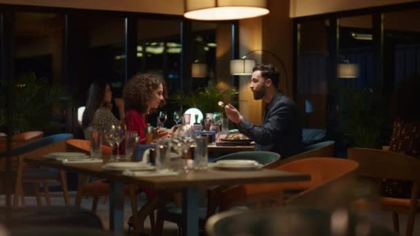 Многорасовая пара делится едой на ужин в итальянском ресторане на романтическом свидании. — стоковое видео