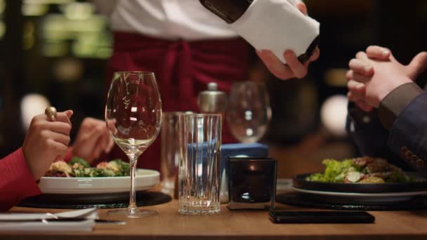 Ober schenkt wijnglas in aan een prima restauranttafel. Paar genieten van luxe dineren. — Stockvideo