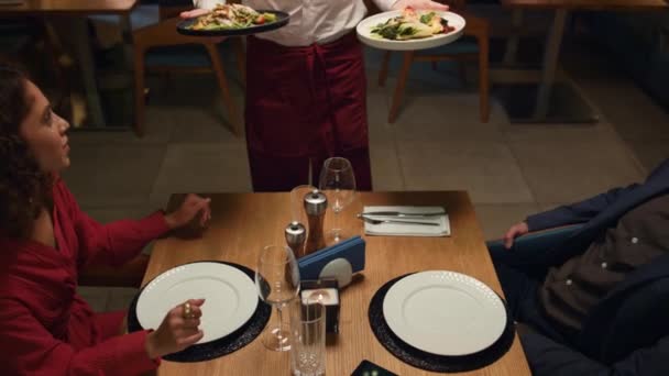 Garçom servindo comida restaurante para casal multiétnico na data de jantar romântico. — Vídeo de Stock