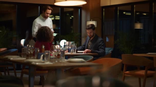 Para zamawiająca kolację w restauracji w nocy. Kelner obsługujący dwóch kochanków na randce. — Wideo stockowe