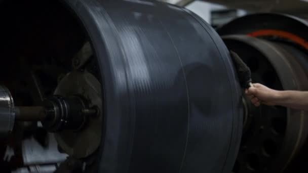 Працівник виробництва шин обробляє гумову стрічку на круглих сучасних машинах — стокове відео