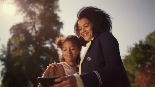 Happy moeder holding smartphone maken selfie met leuke dochter in het voorjaar park. — Stockvideo