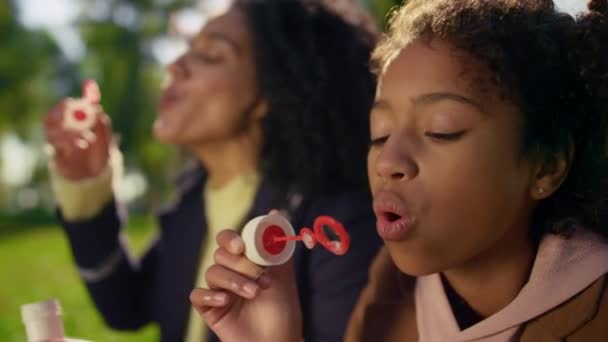 Curly menina soprando sabão colorido bolhas closeup. Momentos de infância despreocupados. — Vídeo de Stock