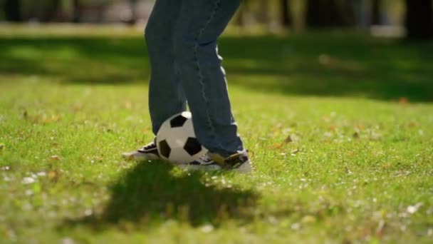 Patadas de cerca pateando pelota de fútbol en el campo verde. Fin de semana activo de verano en parque — Vídeo de stock
