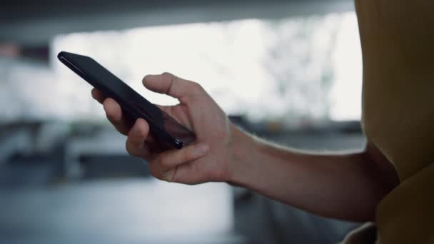 Молодий чоловік вводить повідомлення на скейтпарк мобільних телефонів. Чоловічі руки за допомогою смартфона — стокове відео