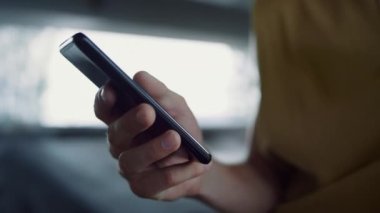 Adam elinde cep telefonuyla kaykay parkına mesaj atıyor. Erkek eli cep telefonuna dokunuyor. 