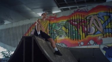 Mutlu kaykaycı kaykay parkında rampada dinleniyor. Yakışıklı adam mola veriyor.. 