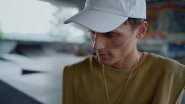 Leuke vent die nieuws leest op de mobiele telefoon in het skate park. Man gezicht naar beneden kijkend. — Stockvideo