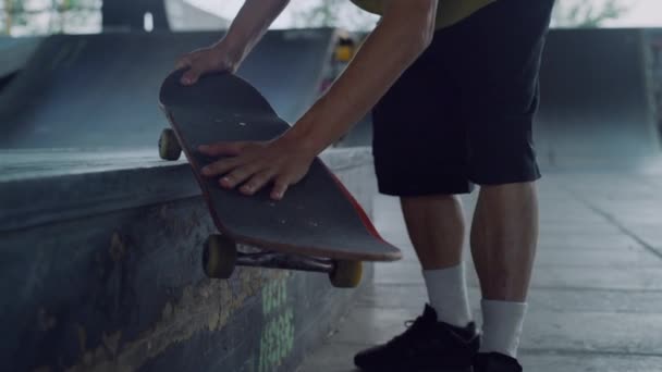 Skateboarder segurando skate bordo em mãos no parque de skate. Homem mãos skate. — Vídeo de Stock