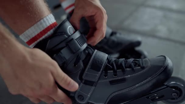 Adolescente activo que se pone patines en el parque de patines. Patas masculinas patines — Vídeo de stock