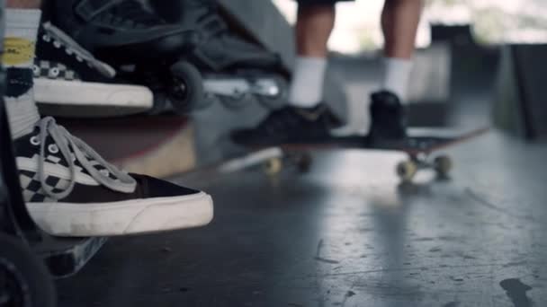 Уставший спортсмен расслабляется после тренировки в скейт-парке. Мужские ноги в кроссовках. — стоковое видео