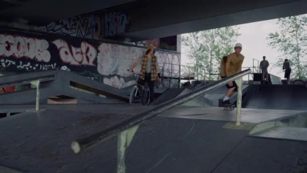 Millennial man performing extreme tricks on rail at urban skate park. — Stock Video