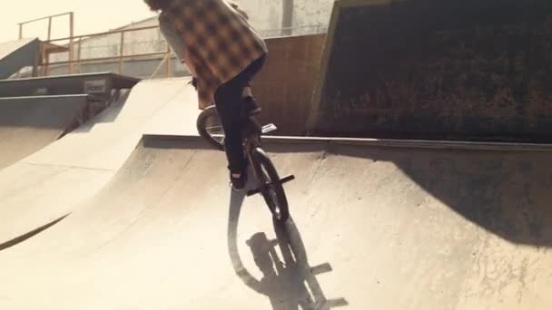 Biker desportivo realizando truques na bicicleta bmx no parque de skate urbano da cidade. — Vídeo de Stock