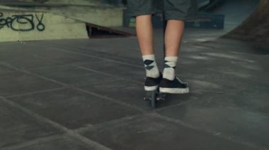 Kentsel kaykay parkında scooter süren sportif çocuk. Dışarıda antrenman yapan sıradan bir sürücü.